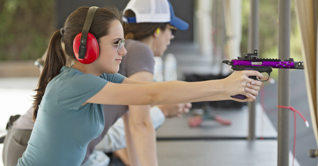 Woman shooting a rimfire competition pistol at a range.
